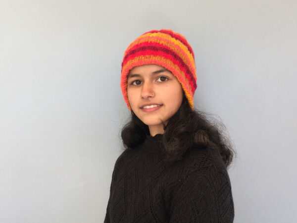hand knit striped, ribbed beanie in varying shades of orange