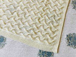 hand knit cream baby blanket in a cables and lace pattern