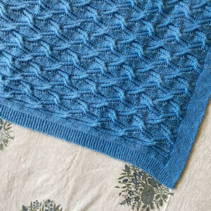 hand knit light blue baby blanket in a cables and lace pattern
